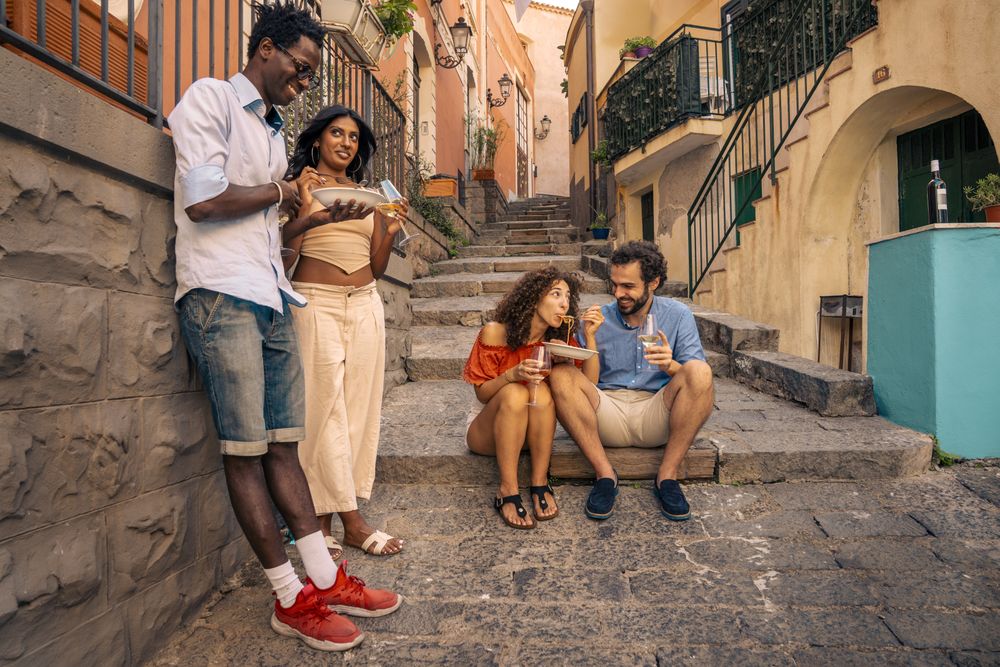 Group of friends eating pasta on the street in an Italian town