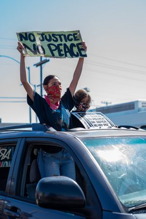 Los Angeles, CA, USA — June 7th, 2020: woman standing through moonroof of car at protest
