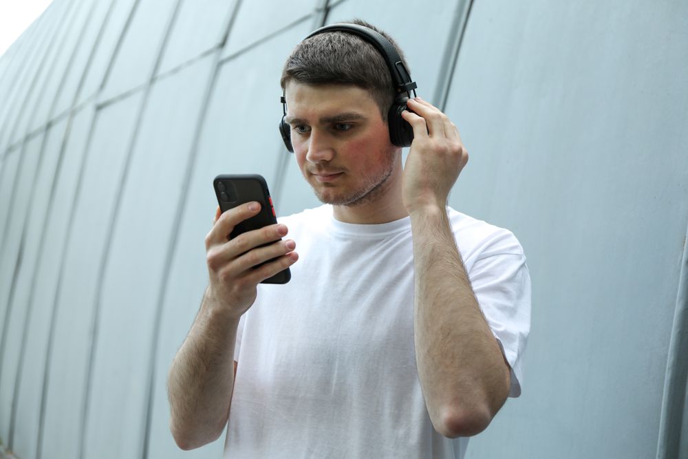 Young man in t-shirt listening to music in headphones