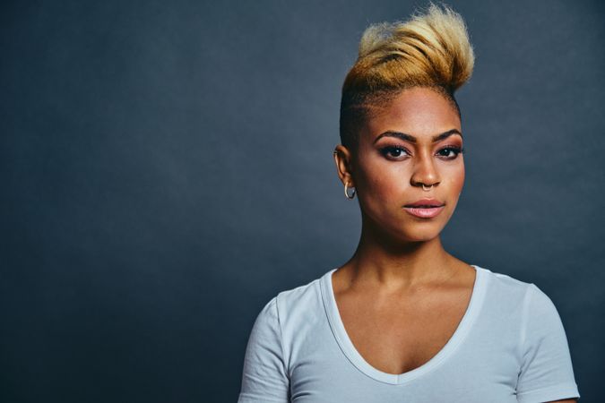 Portrait of serious Black woman with short blonde hair against gray background with copy space