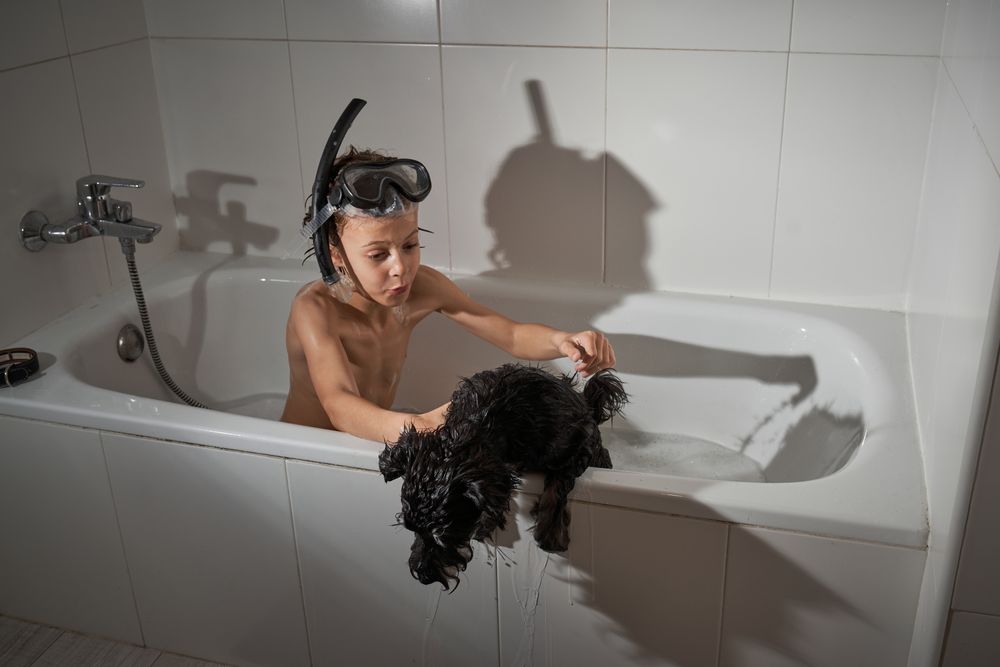Boy with dog in bathtub
