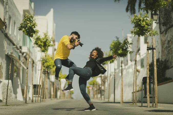 Excited man taking photo of bending girlfriend