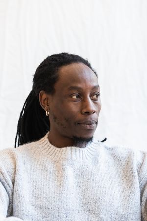 Black man looking away on white wall