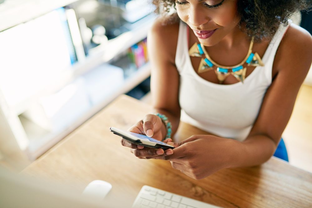 Looking down at woman sitting at her desk using phone