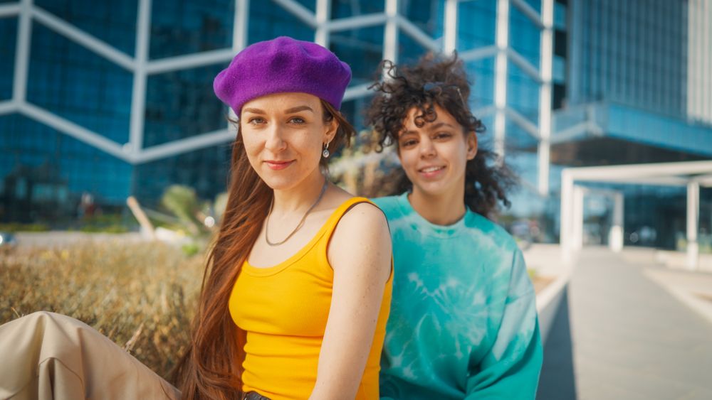 Vibrant Young Women In Colorful Attire Share A Joyful Moment