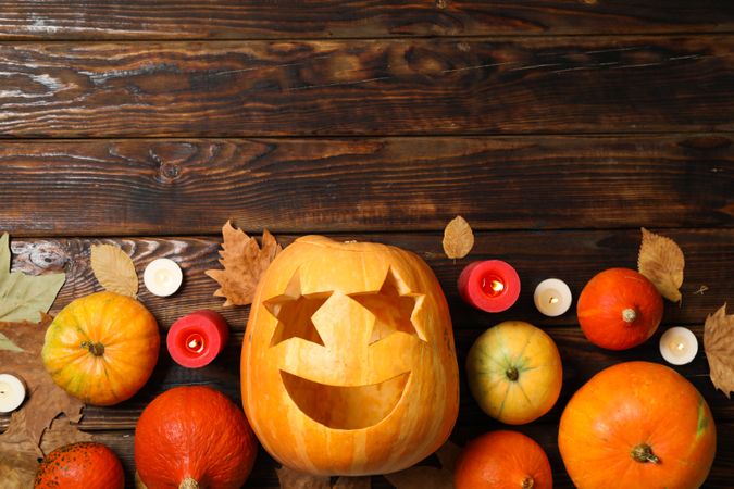 Pumpkins, leaves and candies on wooden background, copy space
