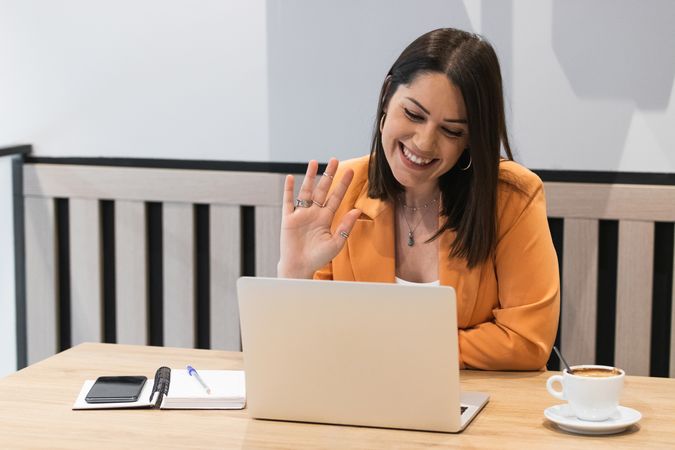 Smiling woman talking on video chat via laptop in cafe