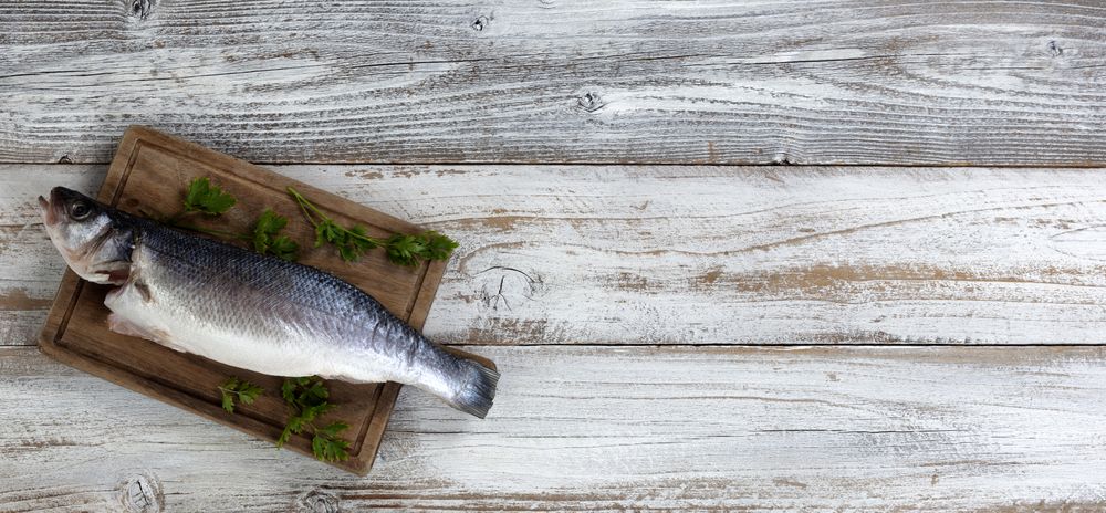 Freshly cleaned seafood seabass fish on rustic wooden table