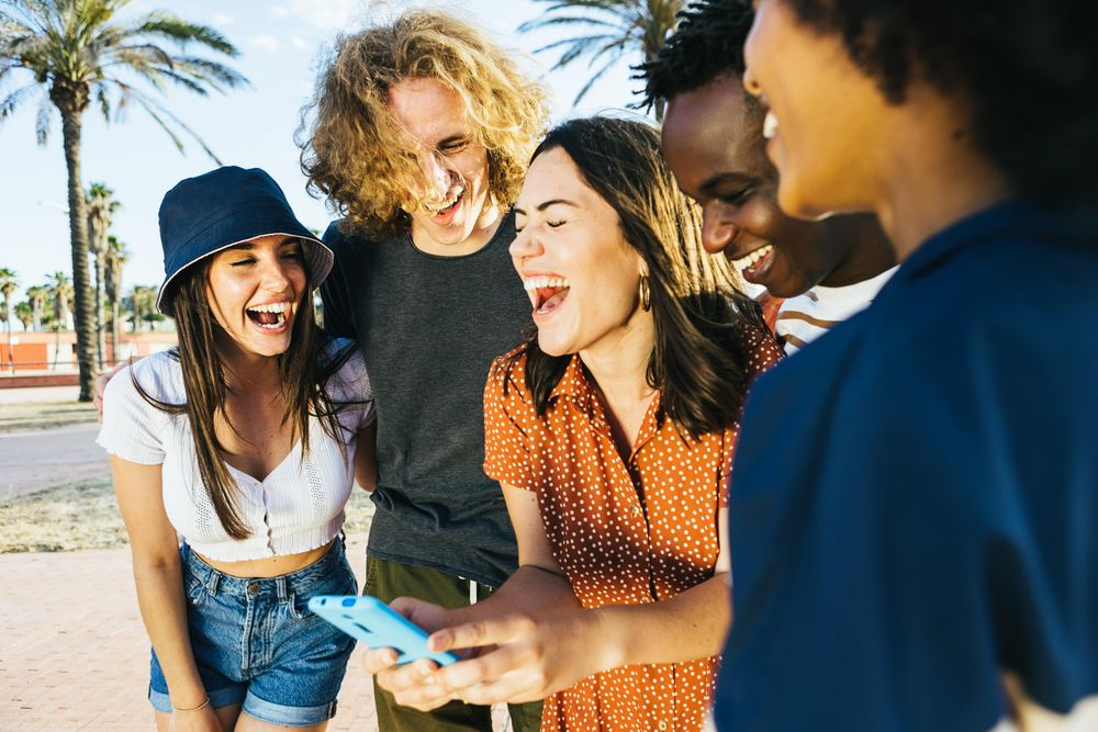 Diverse group of  people having fun and laughing while sharing content on social media