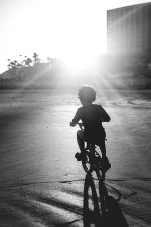 Grayscale photo of boy riding a bicycle