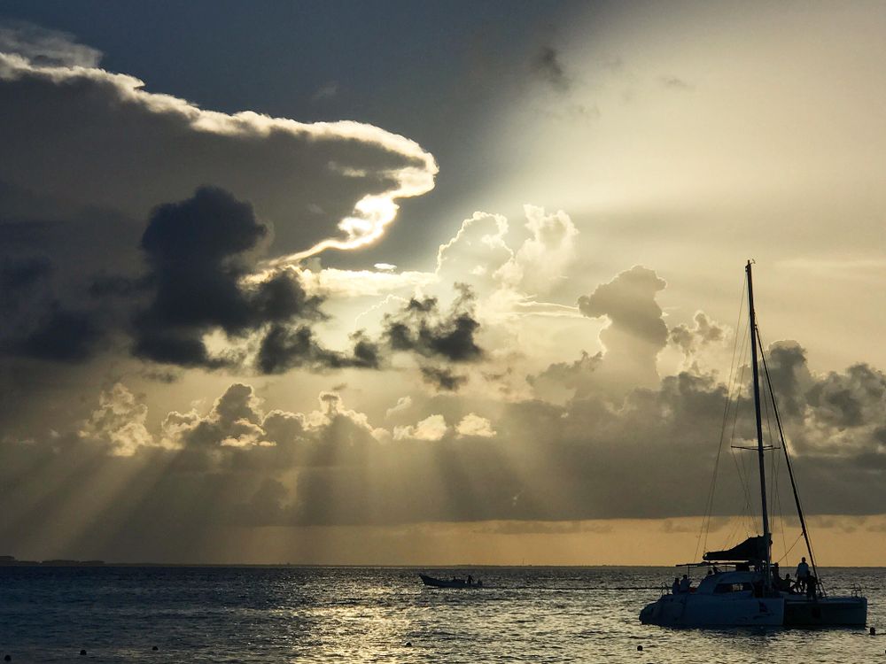 People on boats on sea under cloudy sky