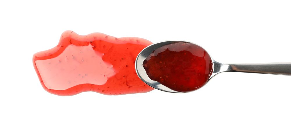Spoon with strawberry jam isolated on plain background