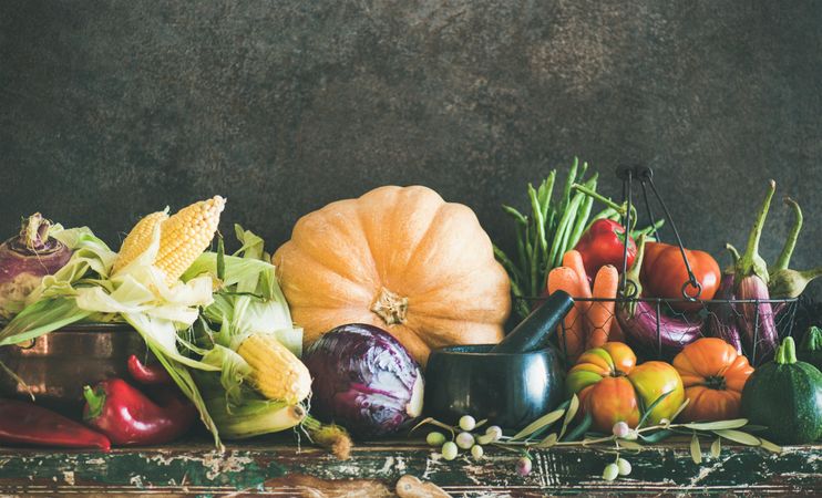 Fresh produce on counter with dark background with central squash, corn, cabbage, with copy space