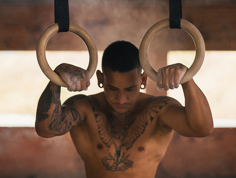 determined male athlete holding gymnastic rings