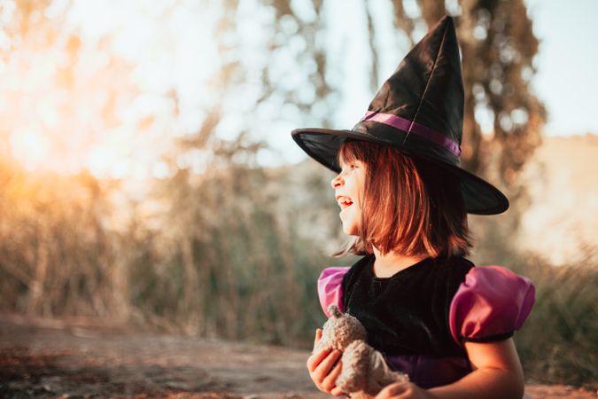 Joyful girl in witch costume at sunset