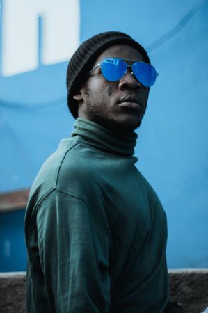 Man wearing turtle neck top, beanie and sunglasses