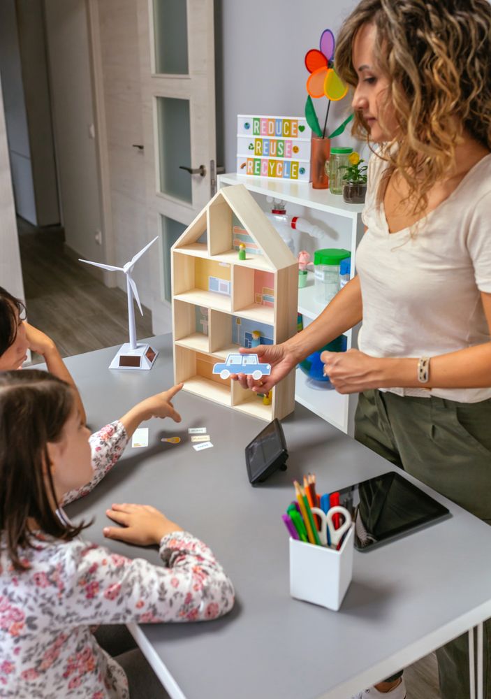 Teacher explaining to her students the parts of a sustainable house showing an electric car