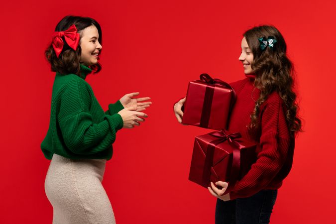 Woman and girl display two large red gifts, happily smiling