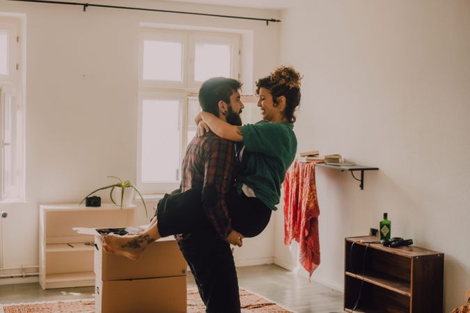 Happy couple embracing in room next to cardboard boxes