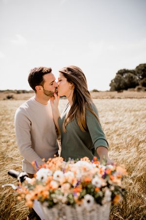 Sincere lovers posing by bicycle on rye field