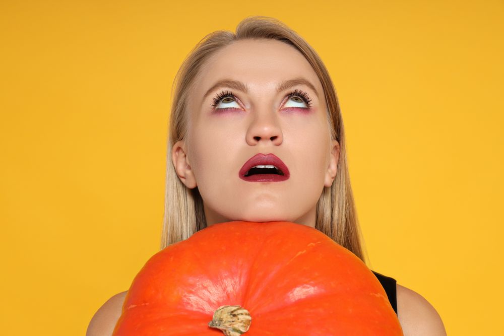 A woman in a Halloween costume with a pumpkin in her hands