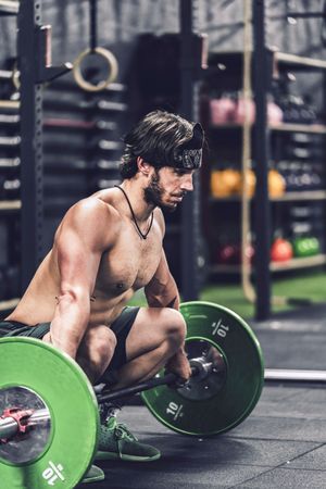 strong and athletic man doing barbell workout in modern gym