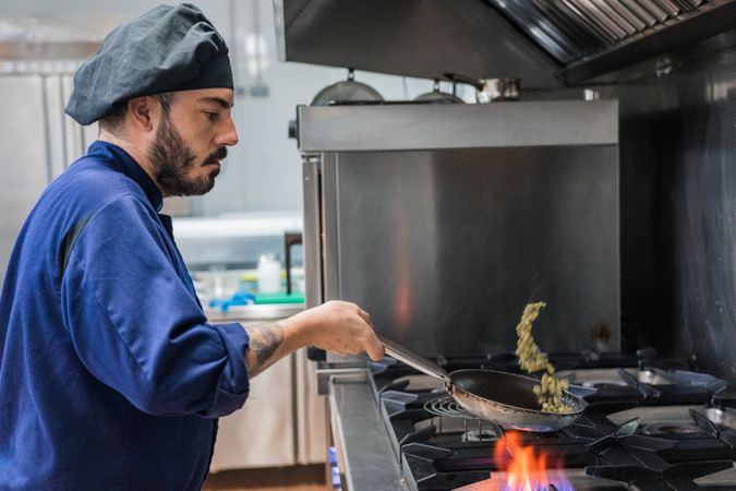 Chef frying vegetables on gas stove