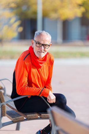 Male looking up while sitting on bench in park