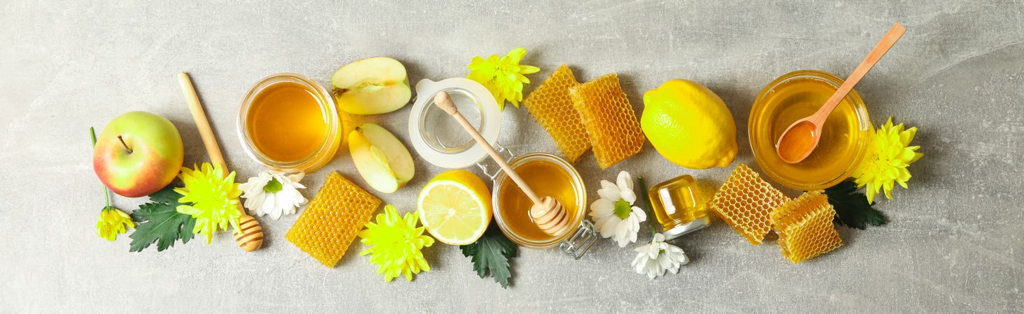 Flat lay with honey, flowers and fruits on grey background, copy space