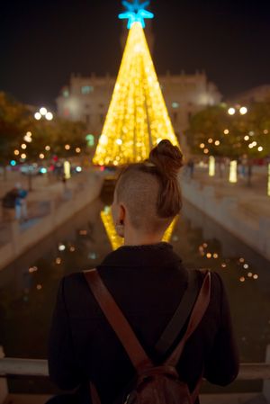 Anonymous woman looking at bright Christmas tree