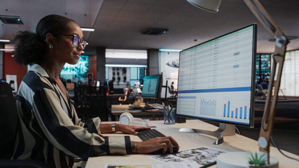 Female Manager Using Desktop Computer With Analytics Software wth Financial Reports.