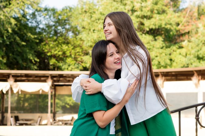 Mom and teenage daughter hugging on walk in park