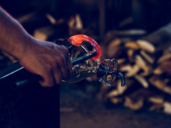 Anonymous craftsman making glass carafe in factory