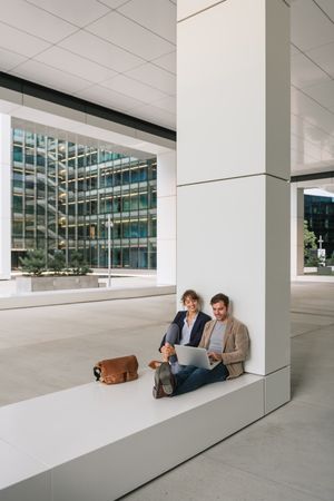 Cheerful colleagues using laptop on street