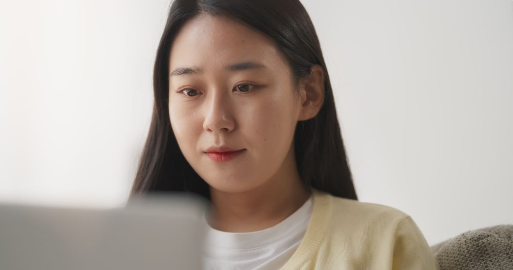 Portrait of a Young Asian Female Browsing Internet, Using Laptop Computer at Home