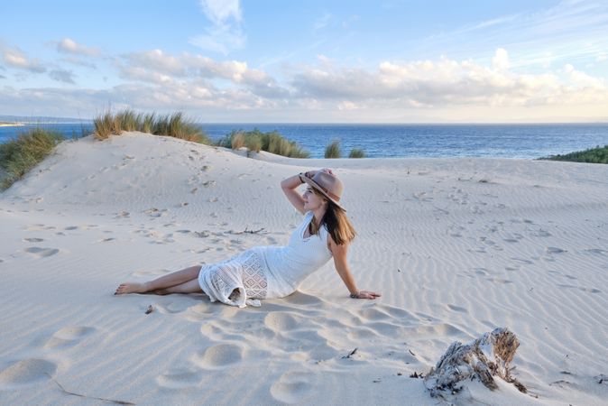 Woman in white dress relaxing on sand