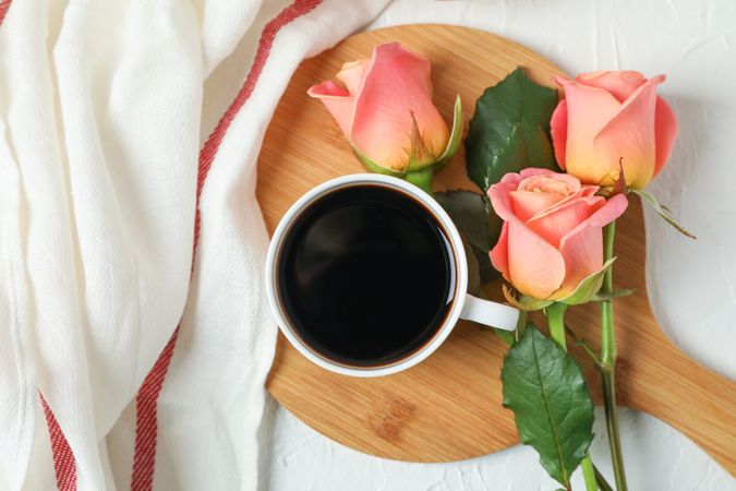 Composition with cup of coffee, roses and kitchen towel, top view