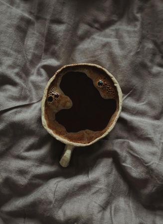 Top view of coffee cup on grey bed