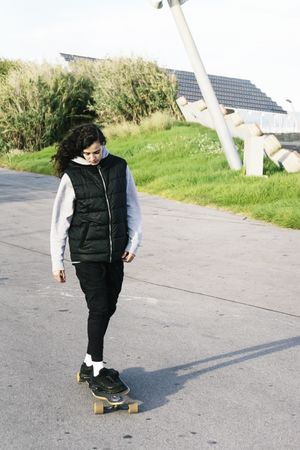 Teenage girl skating on a longboard in a city park