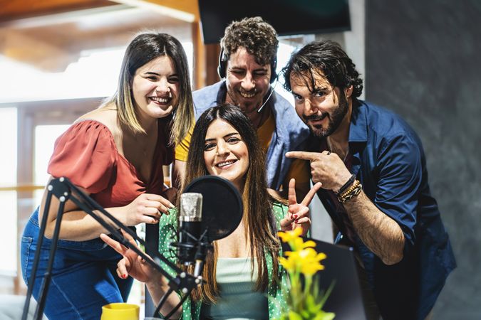 Podcast hosts gathered around microphone in studio