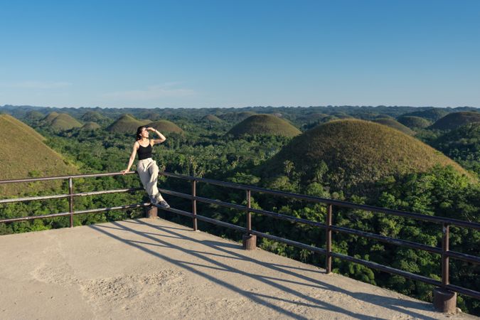 Happy woman standing on observation deck on hill