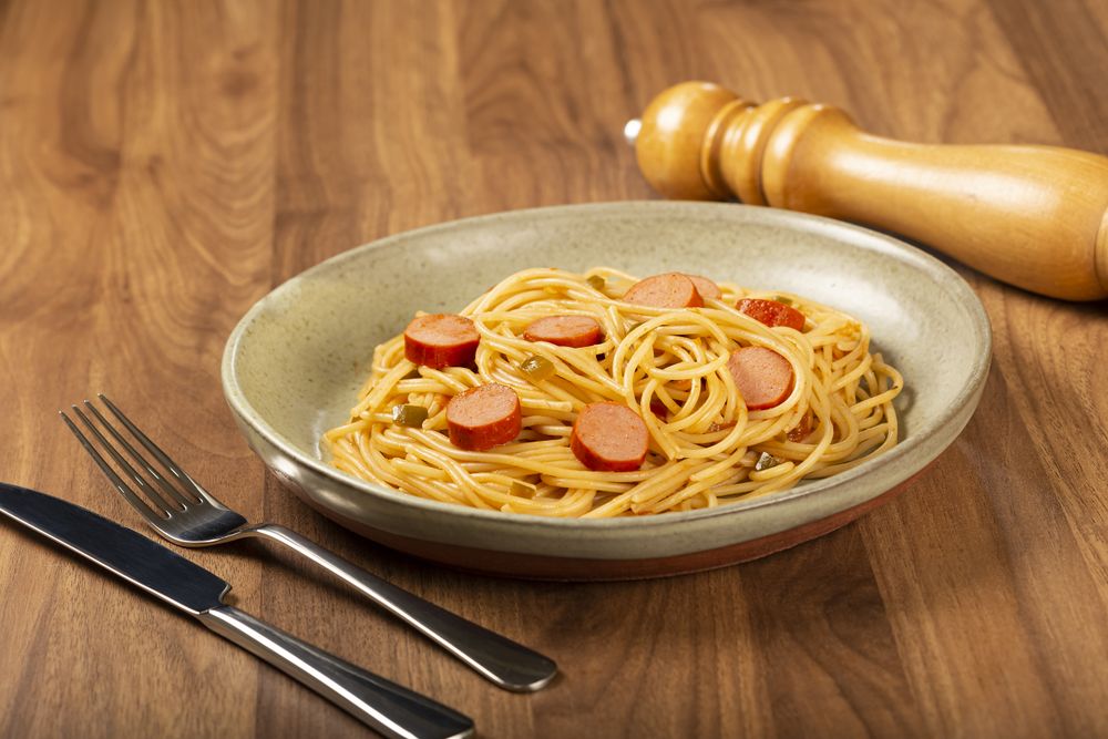 spaghetti pasta with sliced sausages and tomato sauce.