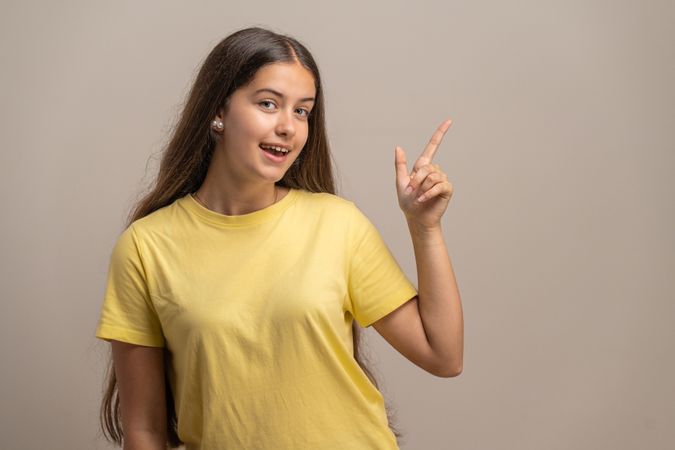Excited young woman pointing to the side at an empty copy space for advertising.