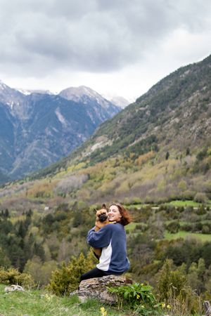 Happy traveling woman with cute dog in highlands