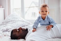 Baby boy lying on his father’s chest and smiling