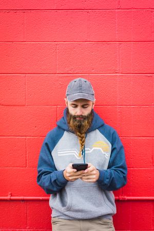 Man using smartphone near red wall