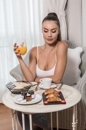 Woman eating breakfast sitting or armchair in a hotel room