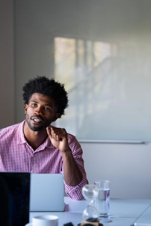 Man with laptop speaking to colleague