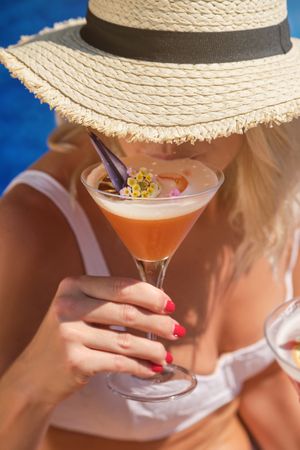 Crop woman in straw hat and bikini with cocktail