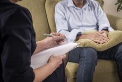 Man holding a pillow for comfort during a therapy session.